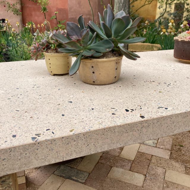 Chelsea Flower Show 2023: waste-based concrete features ♻️ Nurture Garden designed by @sarahpricelandscapes. The majority of the hard landscape features: table, blocks, paver bricks and vessels were made using our low-carbon, waste-based concrete blend. 100% of the aggregates were sourced as waste @crocus.co.uk nurseries, where the fabrication took place. The yellow ochres came from their Bagshot Sand, excavated for a new reservoir, the pink tones came from crushed brick material and over-ordered aggregates. We designed a making strategy to enable quick casting and finishing techniques that could expose the aggregates for decorative and non-slip properties, or more time-consuming polished surfaces for a few special surfaces such as the table and some of the vessel interiors. These features will go on to a new life @benton.end ♻️♻️♻️We will be releasing a series of guidance documents this summer that explain our methodology and will give recipes and advice for making and specifying low-carbon construction materials. The series of documents will start with waste-based concretes 🏋️‍♀️♻️🪨 #lwsjournal @rachel_asl #chelseaflowershow